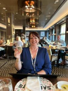 Cath Bracegirdle sits in a luxury cruise bar holding a glass of champagne.