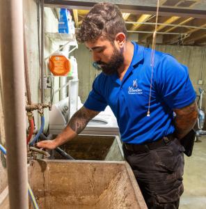 J. Blanton Plumbing technician providing plumbing maintenance, highlighting the company’s commitment to water heater services and 24-hour plumbing as a new member of the Highland Park Chamber of Commerce.