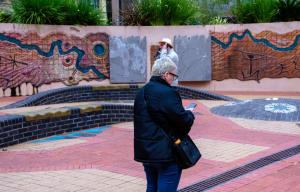 Woman doing a self guided tour on her mobile phone looking at aborginal art