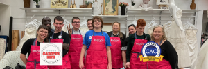 Some participants of the Campus Life Program from Inclusive Supports wearing aprons and beaming at the camera