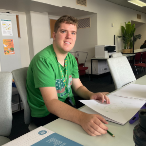 A boy holding a sketchpad and a pencil