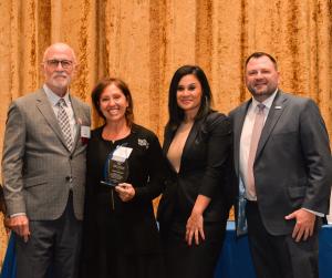 Director Rachel Rossi and CLS CEO Jeff Harvey stand next to award winner.