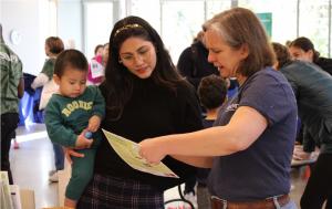 A mother and child receive health information from a volunteer at the health fair hosted by Affordable Homes & Communities, True Ground Housing Partners, and Wesley Housing.