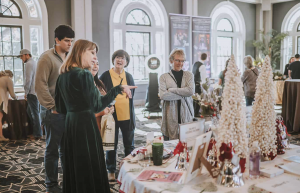 Attendees at the Ultimate Wedding Expo engage with a vendor showcasing wedding decor and ideas at an informational booth