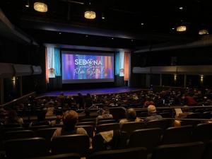 Film screening photo: "Audience seated in a theater at the Sedona International Film Festival, watching a film on a large screen with dramatic lighting