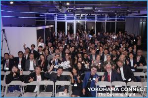 Large group of people sitting in chairs indoors, posing and smiling. Captioned YOKOHAMA CONNÉCT The Opening Night