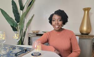 Elaine Swann sitting at a beautifully decorated table, featuring items from her Home Holiday Collection, including stemmed glassware, trays, and candles."