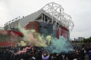 Old Trafford with a group of supporters protesting lighting off flares