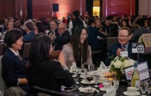 Guests seated at the City of Markham corporate table during the 2024 Business Excellence Awards, sharing smiles and applause. The table is elegantly set with white floral centerpieces, wine, and tableware, reflecting the sophisticated ambiance of the even