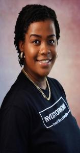 Dr. Linda Pajoel, smiling confidently, dressed in branded company shirt representing her expertise as an author, investment teacher, and advocate for women’s financial empowerment.