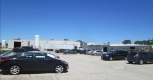 Exterior view of 606 East Murdock Avenue industrial facility showing main building facade with employee parking area in foreground