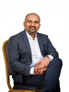 Dr. Rao, seated confidently in a formal suit, recognized as the best neurosurgeon in India and an expert in neuro-oncology and spine surgery. Leading advanced surgical techniques at Dr. Rao's Hospital in Guntur.