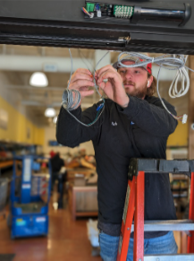 Technician fixing the wiring of an automatic door to restore functionality