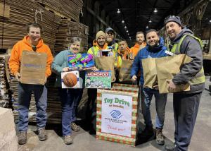 Smiling Premier Metal team members gather around holiday donation boxes filled with toys, celebrating their successful toy drive for Rochester's Boys & Girls Club