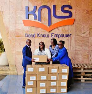 Benvictor Makau (left), Assistant Director, The Trueness Project, presents a donation of 500 Think and Grow Rich books to Mary Kinyanjui (center), Head of Classification, Cataloguing and Distribution Dept and her team. Photo by Godfrey Atsing'a, The Trueness Project.