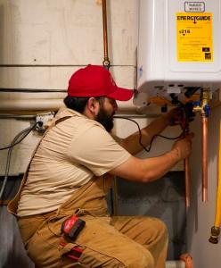 J. Blanton Plumbing technician fixing a tankless water heater, highlighting the company’s expertise in after-hours plumbing, gas line repair, and tankless water heater maintenance to help Chicagoland homeowners recover from winter storm damage.