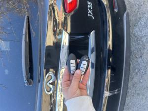 A locksmith holding two newly programmed Infiniti JX35 key fobs, showcasing expert car key replacement services in Las Vegas.