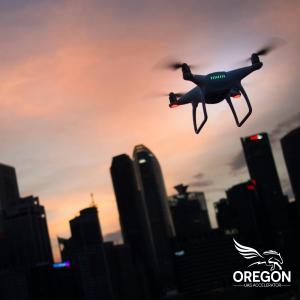 A drone soars over a city skyline at dusk, symbolizing the challenge's focus on urban airspace security. Oregon UAS Accelerator logo.