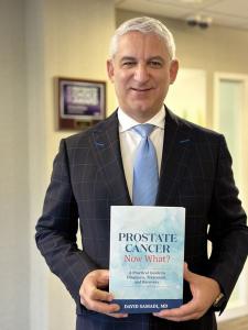 Dr. David Samadi holding book in hallway