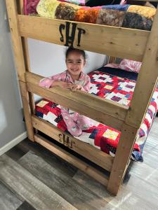 A little girl sits on the bottom bed of a twin-size SHP-branded bunk.