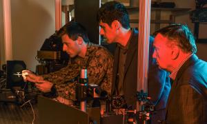 Lasers enable the U.S. Navy to fight at the speed of light Naval Postgraduate School (NPS) faculty researchers Brij Agrawal (right) and Leonardo Herrera observe U.S. Navy Ensign Nicholas Messina positioning a Reaper drone model in an optical beam path to simulate a distant flying drone.