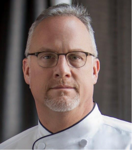 A headshot of a man in a chef's coat.