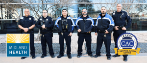 Three police officers in dark uniforms and tactical gear stand in front of a glass building, with logos of Midland Health and a certified autism center visible.