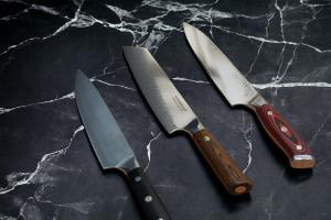 German, Japanese, and American chef pro knives rest on Calacatta Black marble