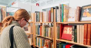 A shopper peruses shelves of books at a rare book fair