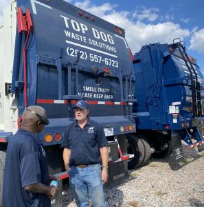 A dumpster rental expert instructs the truck driver to be ready for service.