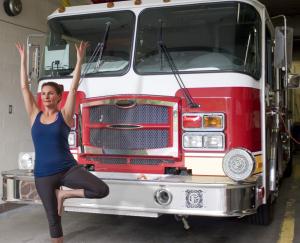 Photo of a woman doing a yoga pose by a firetruck