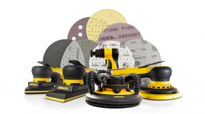 Collection of Mirka sanding pads and polishing machines, arranged in front of various abrasive disc types for marine and automotive detailing.