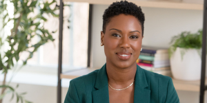 Professional portrait of Dr. Stacey Lawrence seated in a modern, well-lit office space, wearing a green blazer and smiling confidently.
