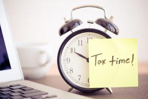 A clock with a note on it saying Tax time!