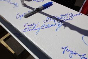 Handwritten word "Finally!" followed by Commissioner Calvert's signature on white painted surface