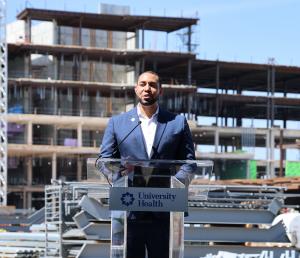 Commissioner Calvert standing at podium in front of construction site