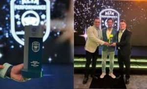 The image shows the award received by the Grand Lakes Vehicles company for the second consecutive year, as well as a ceremony to present this award, with three formally dressed men shaking hands on an illuminated stage.