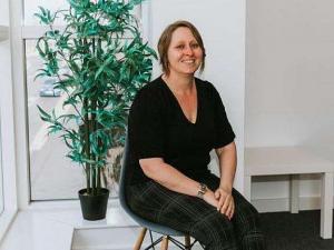 Picture of Alex-Michelle Parr, Managing Director of Wolfestone sat on a chair looking to the camera. She is wearing a black top.