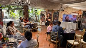 A woman from Love Without Boundaries speaks during a foster care training workshop in Guatemala, as participants listen around decorated tables under a canopy.