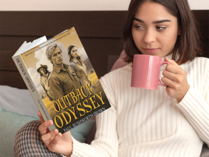 Young woman drinking coffee and reading Outback Odyssey by Paul Rushworth-Brown