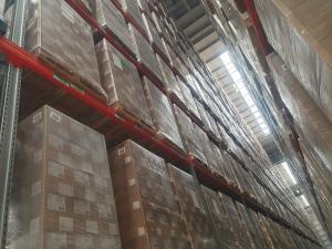 A large warehouse featuring shelves loaded with several pallets arranged in the aisles.
