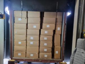 A large truck carrying a 40-foot container filled with hand-loaded boxes stacked on top.
