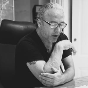 Jack Whatley, a Forbes Speaker and bestselling author, seated at his desk wearing glasses and a headset, mid-conversation during a strategy session for his Automated Content Multiplier Engine.