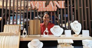 Velani Jewelry Guam pop-up at The Village of Donki featuring 18K gold-filled waterproof and hypoallergenic necklaces on display with founder Velani Junkert.