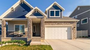 White garage door on a beautiful stone-front house with craftsman-style architecture, large windows, and a wide concrete driveway.