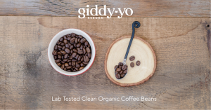 An image of Giddy Yo Coffee Beans in a wood bowl, with logo and text " Lab Tested Clean Organic Coffee Beans"