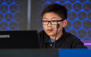 Close-up of a middle school boy onstage, focused while solving a problem.
