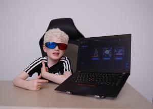 A boy wearing anaglyph glasses engages with the AmblyoFix therapy software on a screen.