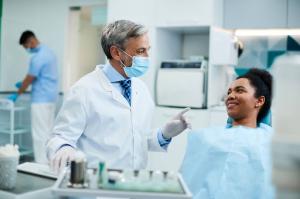  A male dentist explains the procedure to an African American female patient during a routine dental checkup.