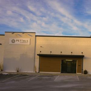 Exterior view of Pettals Cannabis dispensary in Charlton, Massachusetts, with a minimalist white facade, parking spaces, and clear signage.